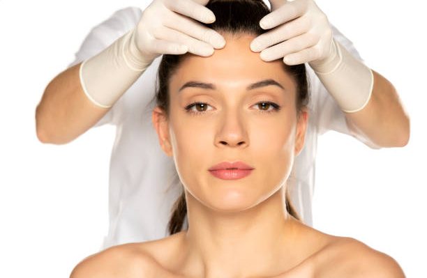 doctor's hands in gloves checks a face of young woman on white background